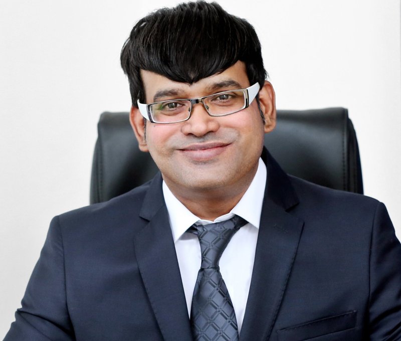 Dr. Sandeep Gupta, head and shoulders portrait in a dark suit and white-framed glasses, about 2018
